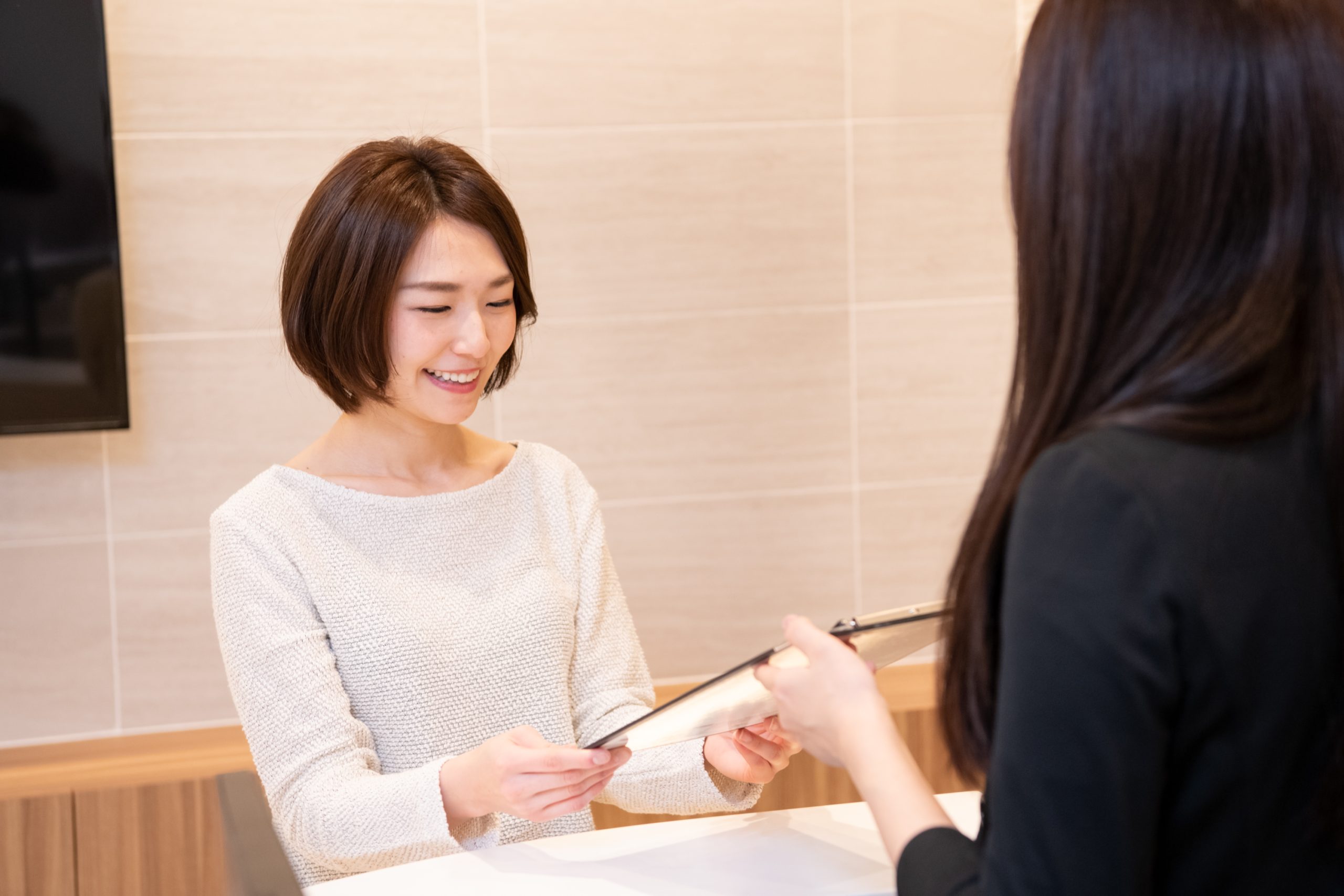 受付で問診表を受け取る女性